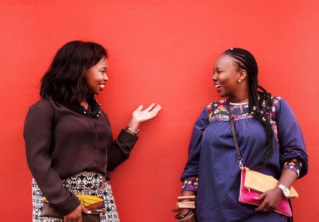 Shot of two female friends chatting against red background