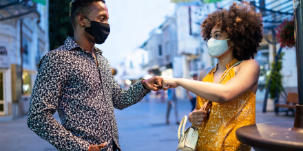 Afro Couple wearing protective face mask walking on the streets and practicing alternative greeting, during COVID-19