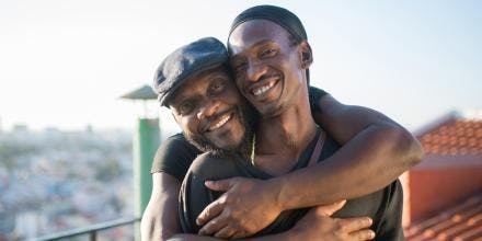 Two black men hugging and smiling at camera