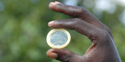 A close-up photo of someone's hand holding a condom
