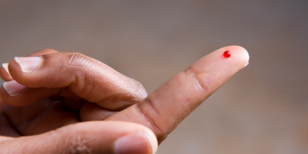 A drop of blood on a young African American woman's fingertip