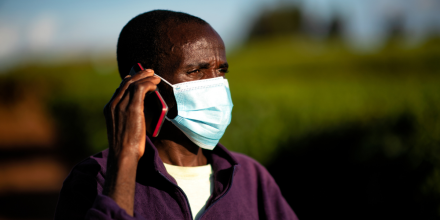 A man wearing a mask talking on a mobile phone
