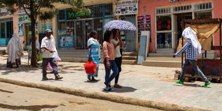 women share an umbrella walking down the road