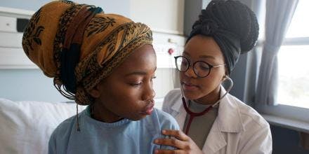 A YounFemale doctor listening with a stethoscope on a young patient's back in a hospital ward in Cape Town South Africa