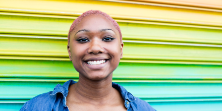 Smiling, confident African American young adult infront of vibrant wall stock photo