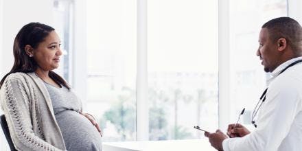 Pregnant woman talking to doctor in clinic 