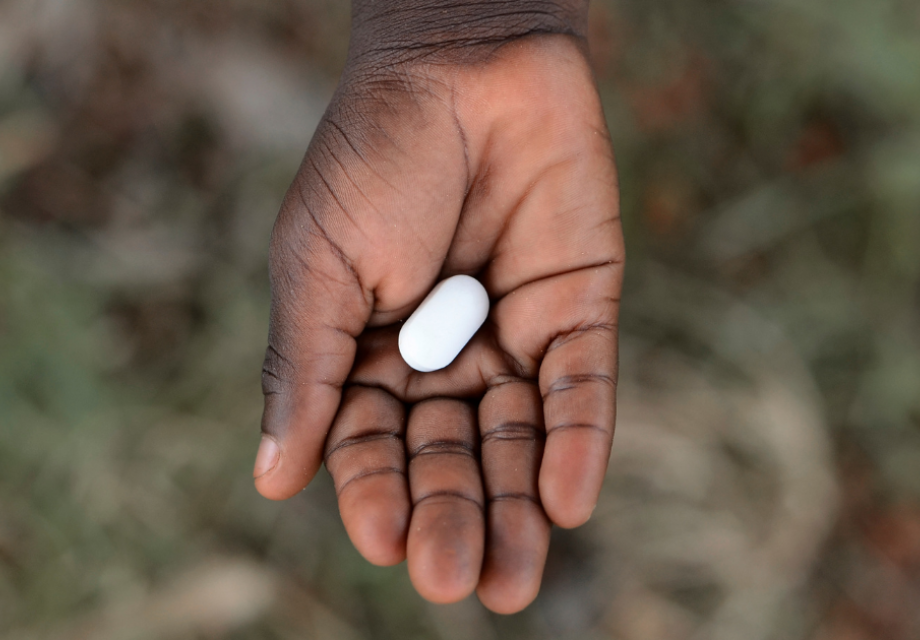 a hand holding a pill