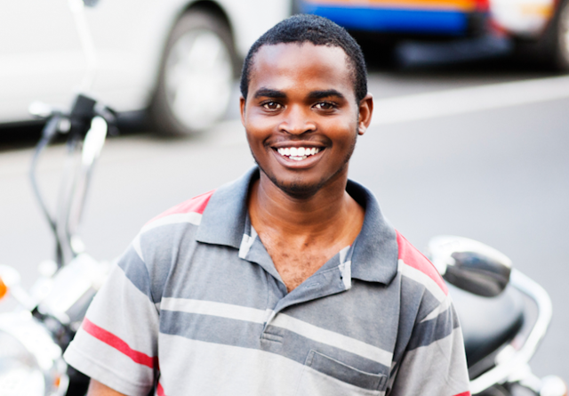 Smiling African man in street with motorbike