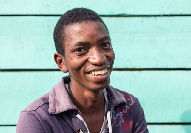 Portrait of African young man smiling happy with colorful wooden wall in the background