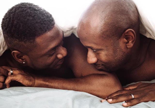 Gay couple in bed gazing in each other's eyes