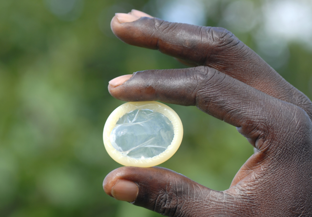 A close-up photo of someone's hand holding a condom