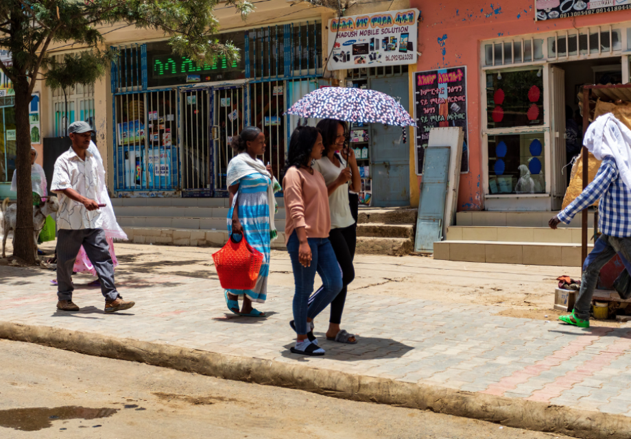 women share an umbrella walking down the road