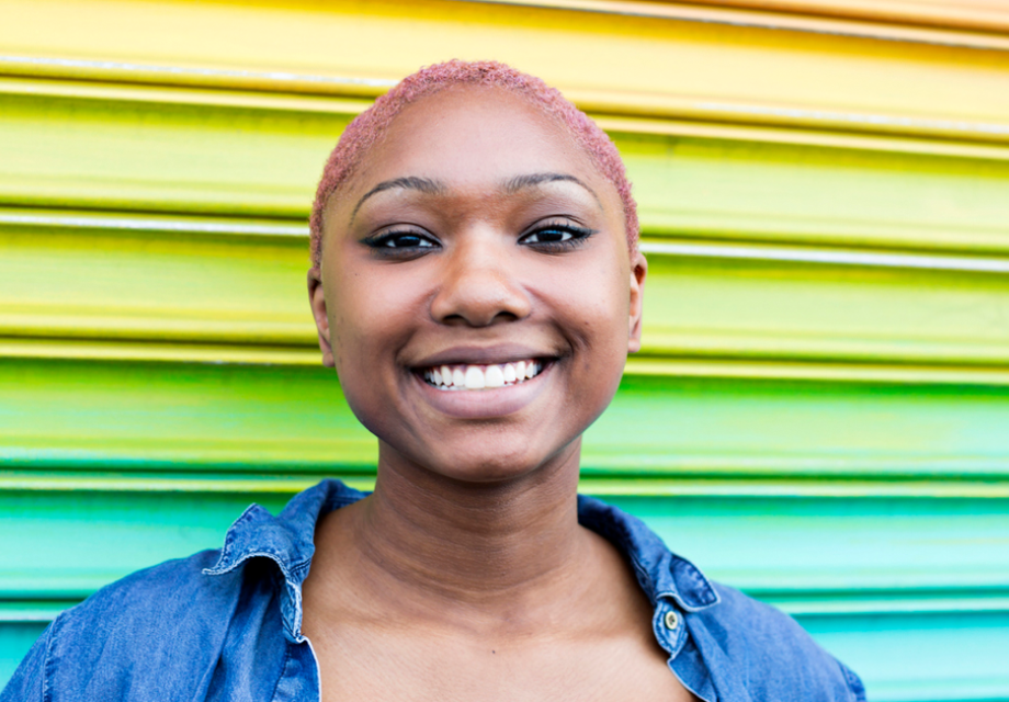 Smiling, confident African American young adult infront of vibrant wall stock photo