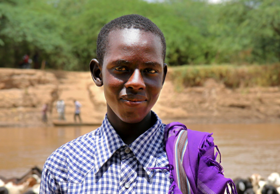 A Kenyan teenage boy standing near a river