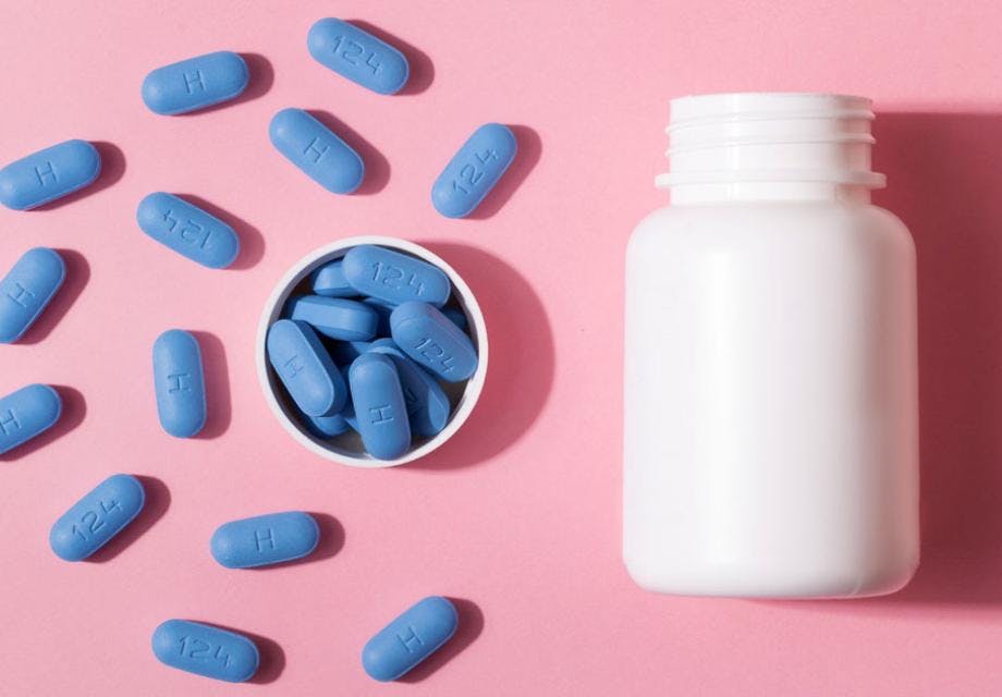 an open bottle of blue prescription PrEP Pills for Pre-Exposure Prophylaxis on a pink background