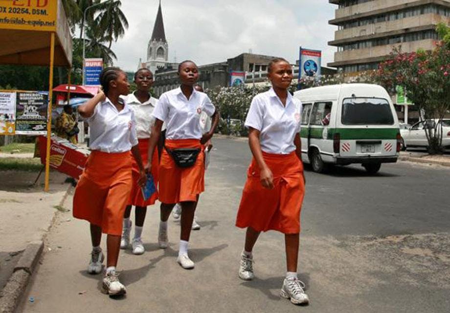 Girls in school uniform walk along a road