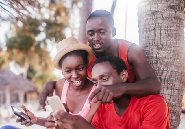 A group of young people in Tanzania looking at a phone and smiling