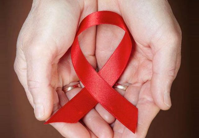 Close up of hands holding a red HIV ribbon