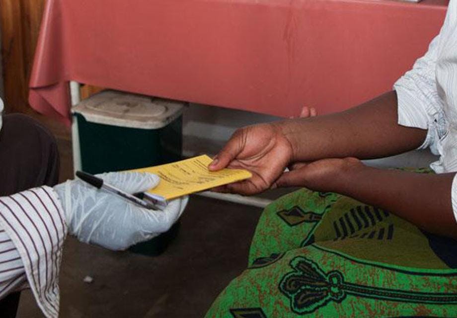 Close up of two peoples hands as a woman receives her health log after testing positive for HIV