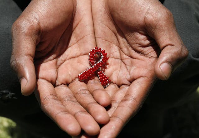 A hand made beaded AIDS symbol in the hands of a black man.