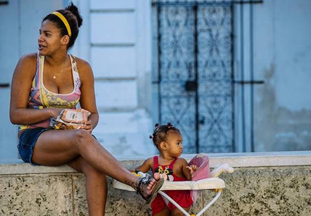 A woman sitting on a wall with her baby in Havana, Cuba