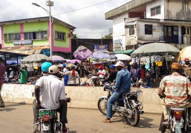 People on motorbikes next to a street market in Cameroon